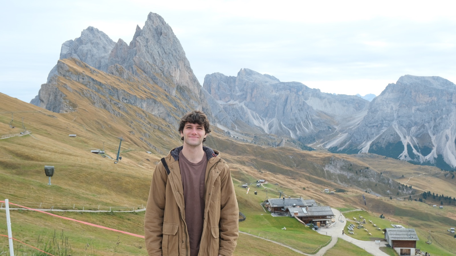 Jack on a grassy ridge in the Dolomites with jagged peaks behind him.